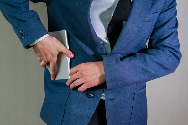 Empresário esconde um tablet em seu bolso casaco — Fotografia de Stock