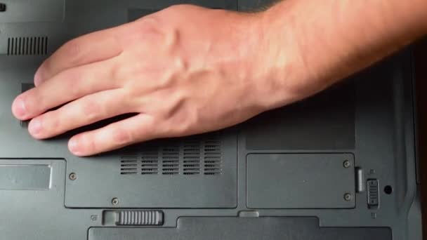 Ремонт ноутбуков. Мужчина открывает заднюю крышку ноутбука отверткой — стоковое видео
