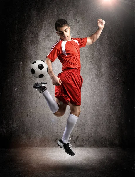 Der Fußballer in Aktion auf dem Wandhintergrund. — Stockfoto