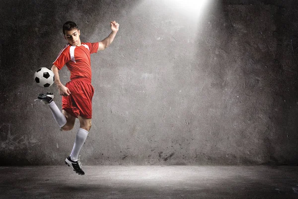 De voetballer in actie op de muur achtergrond. — Stockfoto