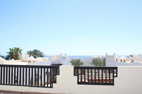 Doğu tarzı tatil beldesinin beyaz çatıları. Ufukta palmiye ağaçları ve deniz var. Mükemmel tatil.