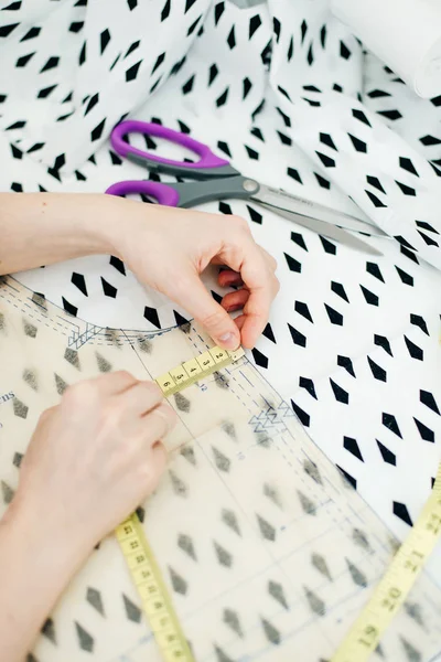 Close-up van een jonge harige vrouw, een naaister snijdt een stuk natuurlijke bont. — Stockfoto