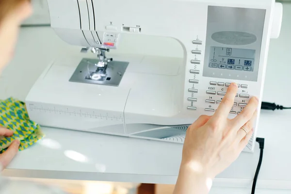 Weibliche Hände nähen weißen Stoff auf professioneller Fertigungsmaschine am Arbeitsplatz — Stockfoto