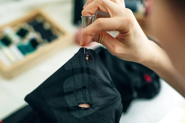 sewer sews up the hole in the pants in studio