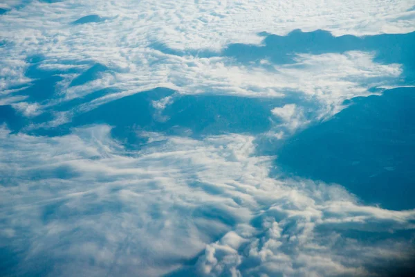 Plane window view of clouds and islands surrounded by sea and airplane wing. Traveling concept — Stock Photo, Image