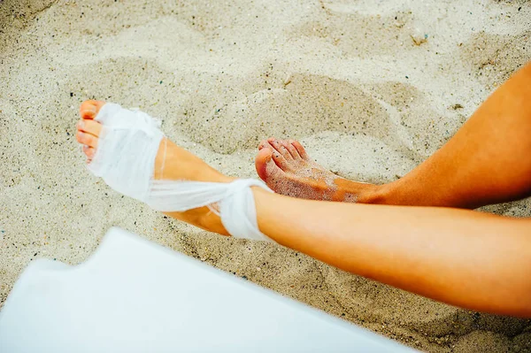 Bendaggio garza i pazienti in cura con l'uomo sta avvolgendo la sua ferita al piede sulla spiaggia — Foto Stock