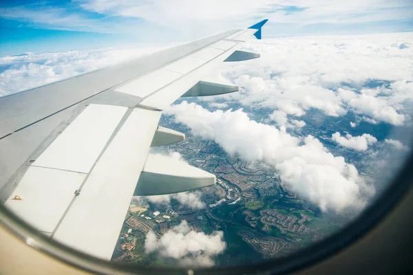 Plane window view of clouds and islands surrounded by sea and airplane wing. Traveling concept — Stock Photo, Image