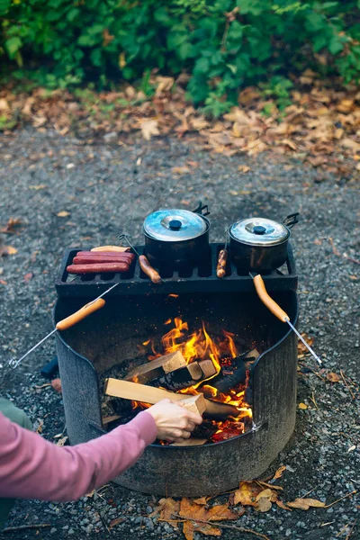 篝火香肠在篝火上，后面有烤架. — 图库照片