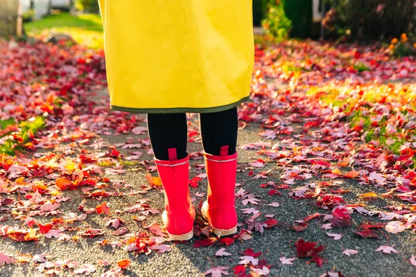 Capa de chuva amarela. Botas de borracha rosa contra. Imagem conceitual de pernas em botas na grama verde . — Fotografia de Stock