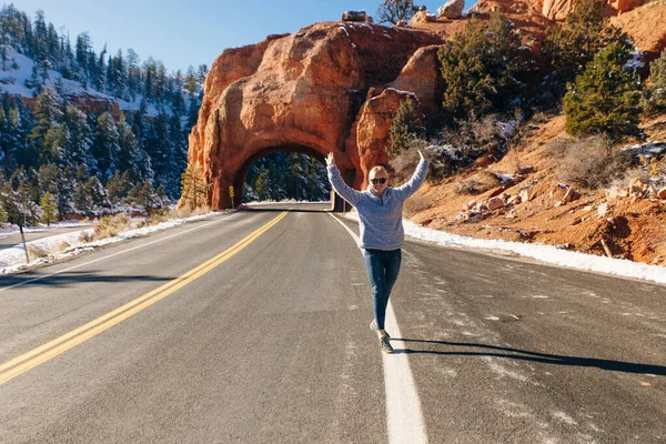背景の少女ブライスキャニオン国立公園、ユタ州、アメリカへ向かう途中の赤いアーチ道路トンネル — ストック写真