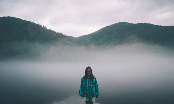 Dziewczyna w koszuli i okularach stoi we mgle na rzece — Zdjęcie stockowe