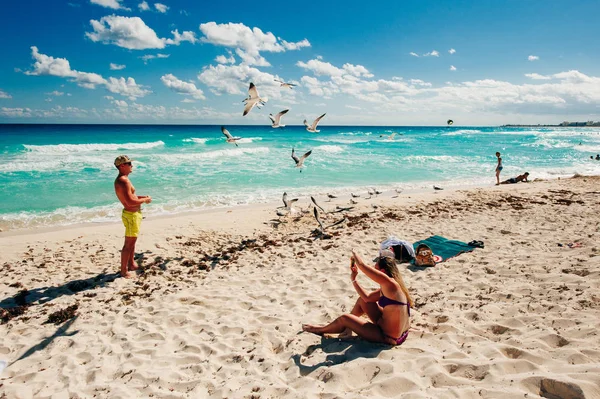 Mexico - Playa Delfines - December, 2019 Beautiful beach in Cancun. Tourist feeds seagulls — Stock Photo, Image