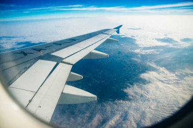 Deniz ve uçak kanadıyla çevrili bulutların ve adaların uçak penceresi manzarası. Seyahat kavramı