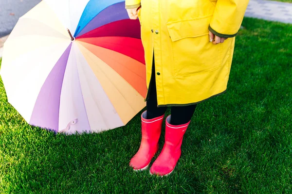 Żółty płaszcz przeciwdeszczowy. Gumowe różowe buty przeciwko. Koncepcyjny wizerunek nóg w butach na zielonej trawie. parasol — Zdjęcie stockowe