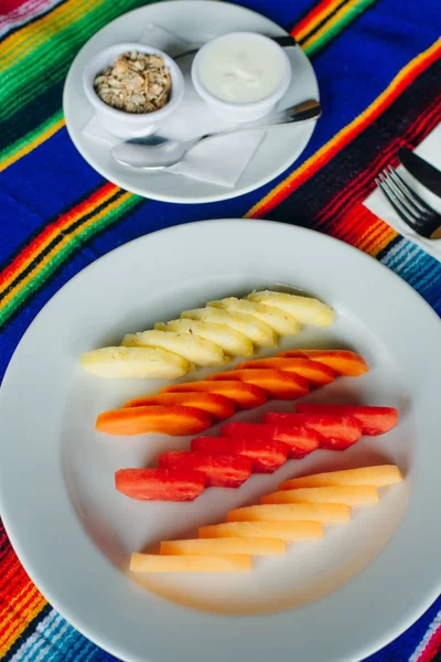 Fatias de frutas lindamente fatiadas em um prato branco em um restaurante. Comida mexicana — Fotografia de Stock