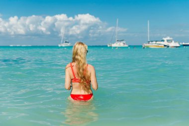 Plajda, Playa Norte, Isla Mujeres 'de kırmızı mayo giymiş güzel bir sarışın. Meksika