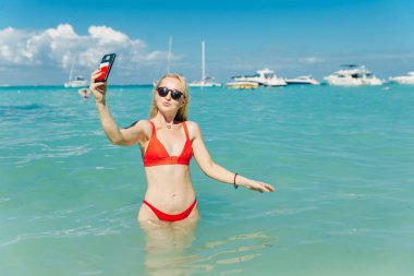 Kırmızı mayolu güzel sarışın Playa Norte, Isla Mujeres plajında selfie çekiyor. Meksika