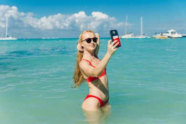 Kırmızı mayolu güzel sarışın Playa Norte, Isla Mujeres plajında selfie çekiyor. Meksika