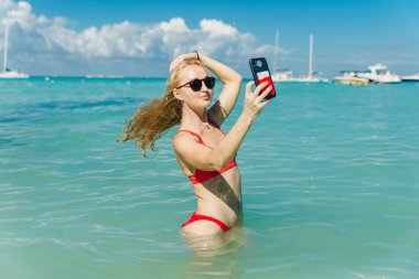 Kırmızı mayolu güzel sarışın Playa Norte, Isla Mujeres plajında selfie çekiyor. Meksika