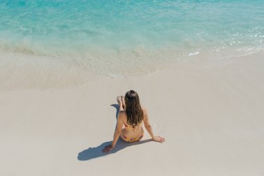 Cancun, Meksika 'da kumsalda oturan parlak mayolu esmer kız.