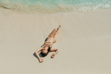 Parlak mayolu esmer kız Cancun, Meksika sahilinde yatıyor.