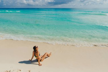 Cancun, Meksika 'da kumsalda oturan parlak mayolu esmer kız.