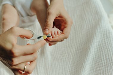 Çocuk tırnağını kesen makas tutan ebeveyn.