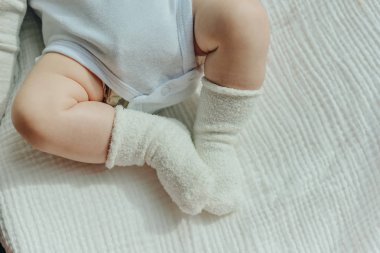 Bebek bacakları. Beyaz çoraplar ve vücut giysisi içinde sürünen bebek. Yukarıdan görüntüle.
