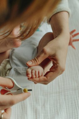 Çocuk tırnağını kesen makas tutan ebeveyn.