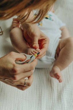 Çocuk tırnağını kesen makas tutan ebeveyn.