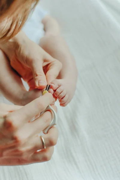 Parent hand holding scissors trimming child toenail Stock Photo