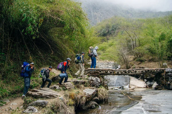 Nepal - settembre, 2019 Gruppo di viaggiatori cammina sul ponte in Himalaya . — Foto Stock