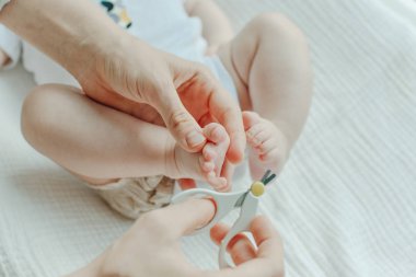 Çocuk tırnağını kesen makas tutan ebeveyn.