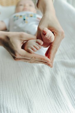 Bacakları yeni doğmuş bebek ve annesinin kolları.