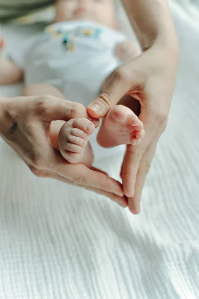 Jambes nouveau-né et bras de maman coeur — Photo