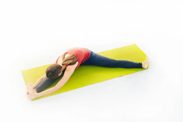 Retrato de vista lateral de una hermosa joven haciendo ejercicio de yoga o pilates sobre fondo blanco — Foto de Stock