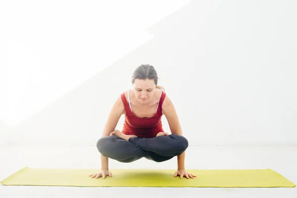 Retrato de vista lateral de una hermosa joven haciendo ejercicio de yoga o pilates sobre fondo blanco —  Fotos de Stock