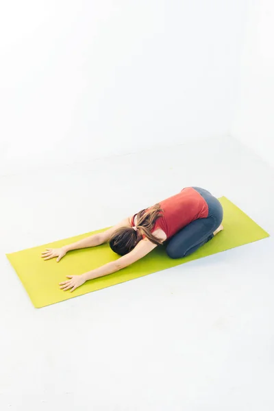 Retrato de vista lateral de una hermosa joven haciendo ejercicio de yoga o pilates sobre fondo blanco —  Fotos de Stock