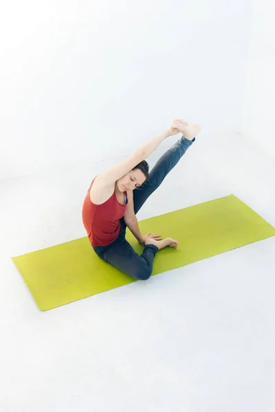 Retrato de vista lateral de una hermosa joven haciendo ejercicio de yoga o pilates sobre fondo blanco — Foto de Stock