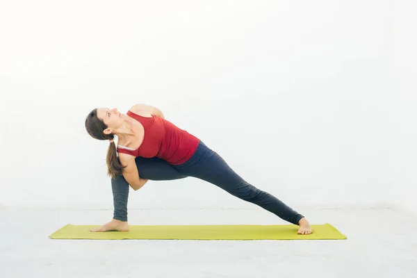 Retrato de vista lateral de una hermosa joven haciendo ejercicio de yoga o pilates sobre fondo blanco —  Fotos de Stock