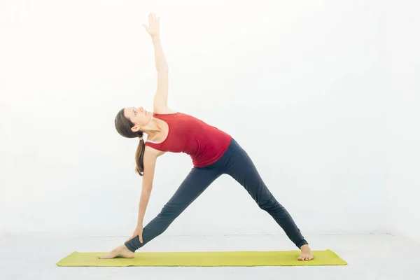 Side view portrait of beautiful young woman doing yoga or pilates exercise on white background — Stock Photo, Image