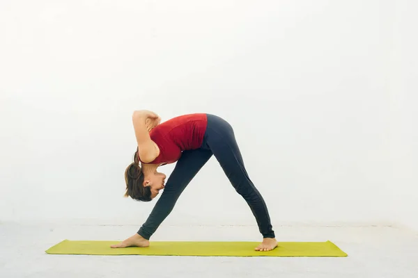 Retrato de vista lateral de una hermosa joven haciendo ejercicio de yoga o pilates sobre fondo blanco —  Fotos de Stock