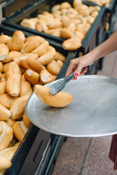 Frauen wählen Brot im Supermarkt. Brötchenzange und Tablett — Stockfoto