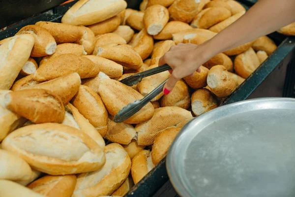 Frauen wählen Brot im Supermarkt. Brötchenzange und Tablett — Stockfoto