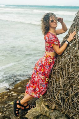 Okyanusun arka planında parlak elbiseli sarışın.