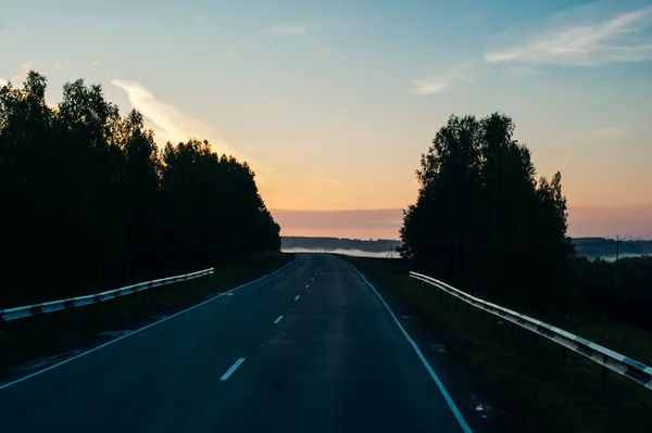 Восходящее солнце убирает асфальт на открытой дороге в солнечное утро — стоковое фото