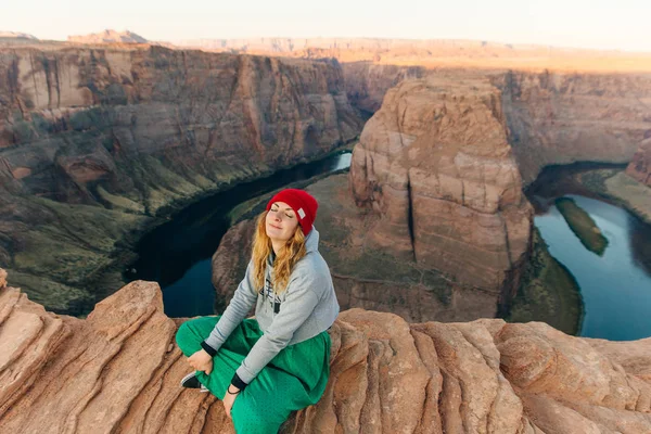 Blonde girl sitting Horseshoe Bend in Glen Canyon National Recreation Area in early dawn — Stock Photo, Image