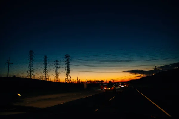 Лінії електропередачі на тлі заходу сонця над горами — стокове фото
