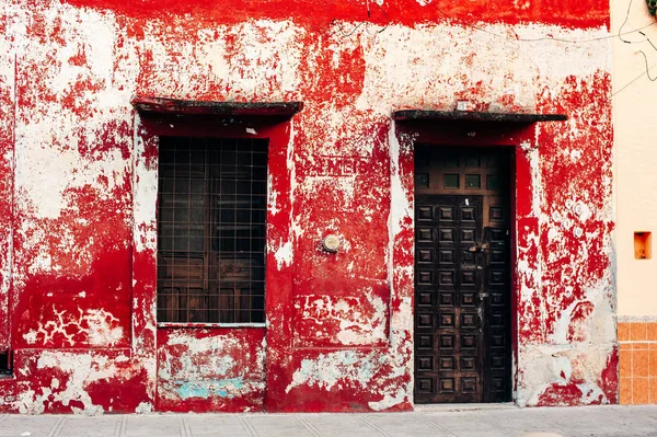 Gammalt sjabbigt rött hus med brundörr i Merida, Yucatan - december, 2019 — Stockfoto