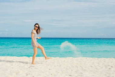 Yalnız ve çekici bir kız, saçlarında rüzgarla sakin denize bakıyor.